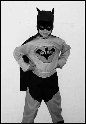 small defiant boy in oversized Batman costume